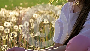 Beautiful springtime beginning of a new life. cute little girl collect dandelion seeds and blows them in wind blown. concept renew