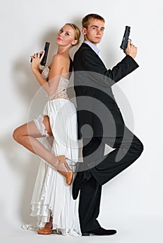 Beautiful spy couple in evening dress with a guns.