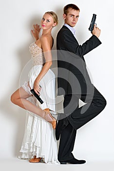 Beautiful spy couple in evening dress with a guns.