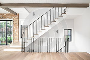 A staircase with wood flooring, wrought iron railings, and wood beams and shiplap ceiling. photo