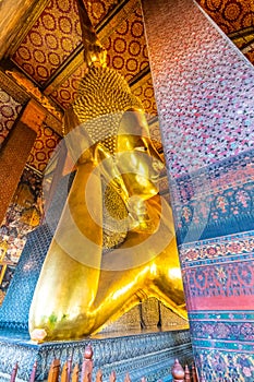 Beautiful statue of reclining golden Buddha placed in Wat Pho temple, Bangkok. Spiritual place of buddhism religion with beautiful
