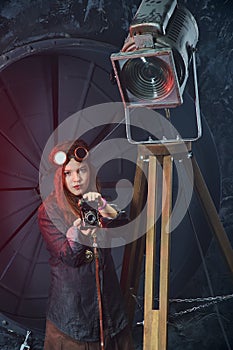 Beautiful steampunk teen girl  in goggles with old camera