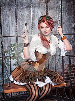 Beautiful steampunk woman in the cage with gun