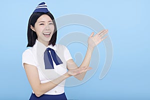 Beautiful stewardess showing something on blue background