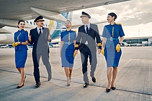 Beautiful stewardesses and handsome aviators walking along the airdrome