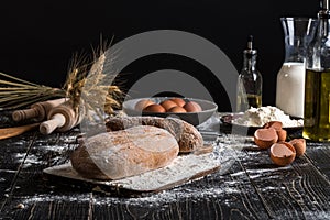 Beautiful still life with different kinds of bread, grain, flour on weight, ears of wheat, pitcher of milk and eggs