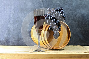 Beautiful still life with glass of red wine against background of oak wine barrel with red wine