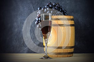 Beautiful still life with glass of red wine against background of oak wine barrel with red wine