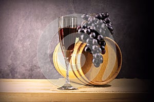 Beautiful still life with glass of red wine against background of oak wine barrel with red wine