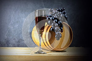 Beautiful still life with glass of red wine against background of oak wine barrel with red wine