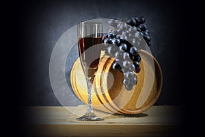 Beautiful still life with glass of red wine against background of oak wine barrel with red wine