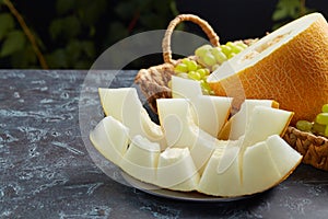 Beautiful still life with a melon on a dark background. Sliced slices on a black plate. Food,Fruits or healthcare