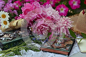 Beautiful still life with peony flowers and book on the table in the garden
