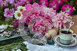 Beautiful still life with peony flowers, decorated book and tea cup on the table.