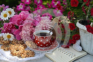 Beautiful still life with peony flowers, vintage cup and cookies on the table.