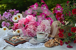 Beautiful still life with peony flowers, vintage cup and cookies on the table.