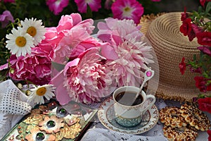 Beautiful still life with peony flowers, vintage cup and cookies on the table.