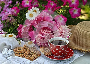 Beautiful still life with peony flowers, vintage cup and cookies on the table.