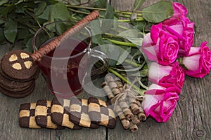 Beautiful still life from roses, cookies and tea on a wooden table