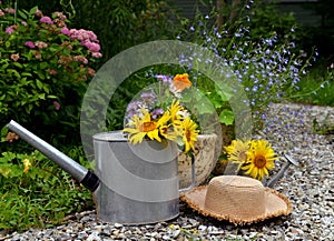 Beautiful still life with sunflowers, watering can and hat in the garden.
