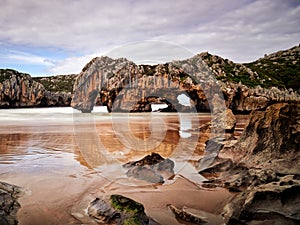 Beautiful stone arches on Playa de las Cuevas del Mar, Cantabria, Spain photo