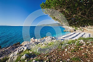 Beautiful stone beach with crystal clear tourquise sea surrounding by pine tree in Croatia, Istria, Europe