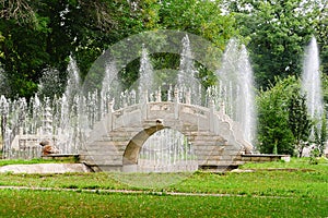 Beautiful stone bridge in traditional chinese park on background of fountains