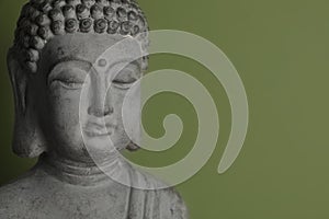 Beautiful stone Buddha sculpture on green background. Space for text