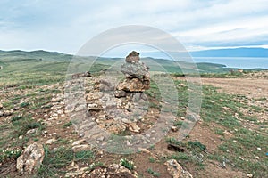 Beautiful stone outlier or rock formation against the background of mountains and Baikal lake. Summer mountain landscape.