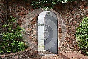 In the beautiful stone wall the iron door is ajar