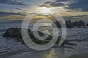 Stones on sand beach and white waves in the sea in morning light