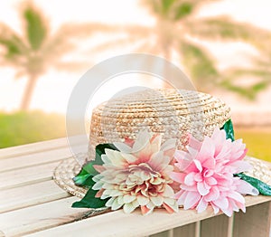 Beautiful straw hat decorated with artifucial flowers on wood ta