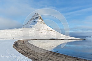 A beautiful stream and Kirkjufell mountain covered with snow during winter in Iceland