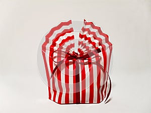 Beautiful striped packing bag tied with a red ribbon with a bow. Gift wrap. Nice gift, surprise.