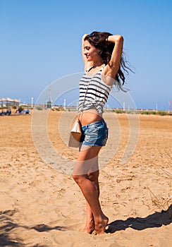 Beautiful strong enjoying woman posing on the beach in blue shor