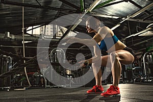 Beautiful strong sporty woman doing crossfit exercise with battle ropes