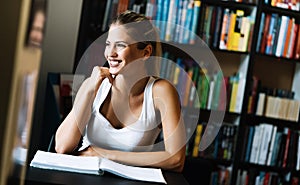 Beautiful student girl studying, reading book at home