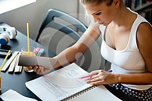 Beautiful student girl studying, reading book at home