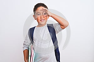 Beautiful student kid boy wearing backpack holding books over isolated white background with happy face smiling doing ok sign with