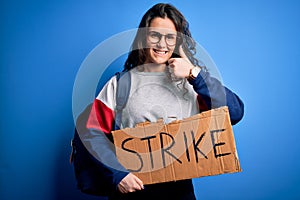 Beautiful student woman with curly hair wearing backpack holding banner with strike message happy with big smile doing ok sign,