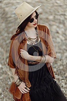 beautiful stylish boho woman in sunglasses and hat, fringe poncho and leather bag. hipster girl in gypsy look young traveler