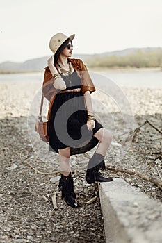 beautiful stylish boho woman in sunglasses and hat, fringe poncho and leather bag. hipster girl in gypsy look young traveler