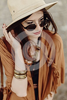 beautiful stylish boho woman in sunglasses and hat, fringe poncho and leather bag. hipster girl in gypsy look young traveler