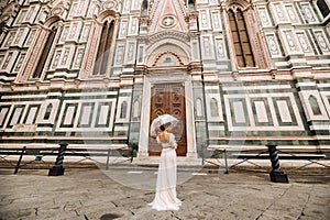 A beautiful stylish bride with an umbrella walks through the old city of Florence.Model with umbrellas in Italy.Tuscany