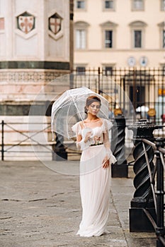 A beautiful stylish bride with an umbrella walks through the old city of Florence.Model with umbrellas in Italy.Tuscany