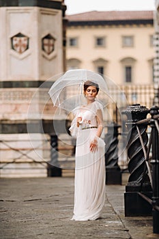 A beautiful stylish bride with an umbrella walks through the old city of Florence.Model with umbrellas in Italy.Tuscany