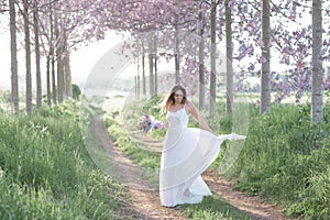Beautiful stylish bride in a wedding dress dancing in a spring forest .