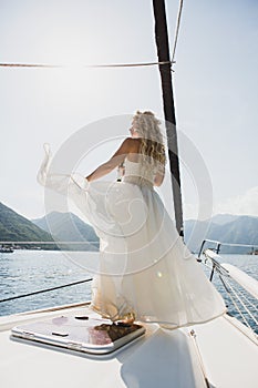 Beautiful stylish bride in a white wedding dress on luxury yacht