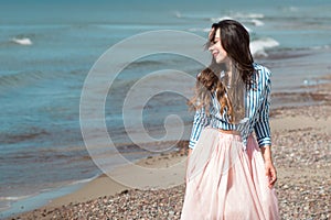 Beautiful and stylish brunette walking on the beach. Portrait in the surf