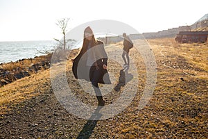 Beautiful and stylish couple walking on a rocky beach. Couple dressed in jackets, hats and boots